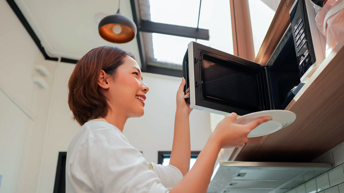 une personne réchauffe un plat avec un four à micro-onde pose livre